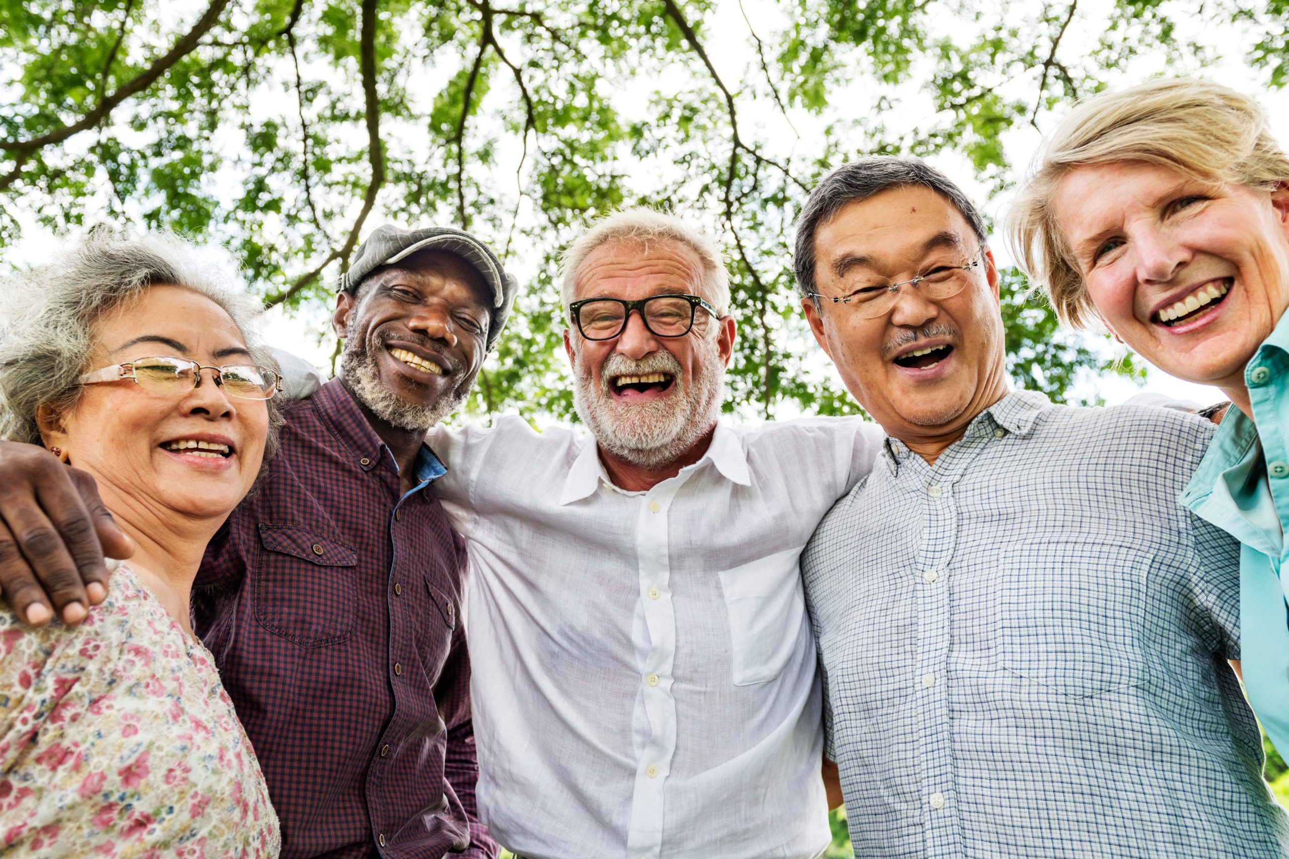 A group of five people of different ages smiling with arms around each others' shoulders.
